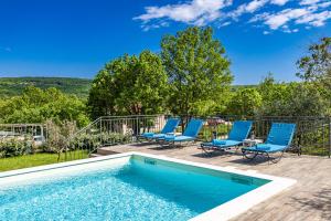 una piscina con sillas azules y una terraza en Krasna kuća, en Labin