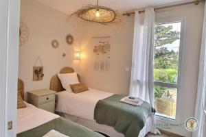 two beds in a room with a window at Ker touro in Trégastel
