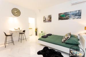 1 dormitorio con cama, escritorio y reloj en The Little Prince apartman Herceg Novi, en Herceg-Novi