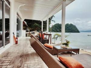 a porch with chairs and a table and the water at Orange Pearl Beach Resort in El Nido
