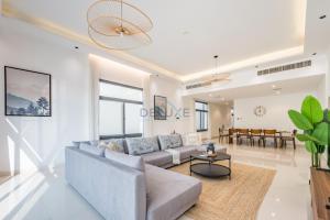 a living room with a couch and a table at Blue Marble Beach 4BR Villa with Assistants Room, Private Pool, Access to Floating Pier, and Sea and Mountain Views, Al Dana Island, Fujairah by Deluxe Holiday Homes in Fujairah