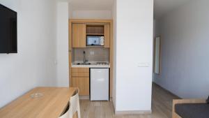 a small kitchen with a table and a refrigerator at Sunside Ibiza Studios - Only Adults- Formerly known as Central Park in San Antonio