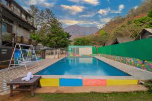 a swimming pool with a bench in front of a building at The Hill Mount Resort Shivpuri in Rishīkesh