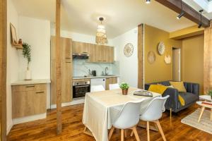 a kitchen and a living room with a table and chairs at Le Boho - Charmant T3 avec climatisation et fibre in Bergerac +10 photos