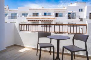 a table and chairs on a balcony with a building at Sunside Ibiza Studios - Only Adults- Formerly known as Central Park in San Antonio