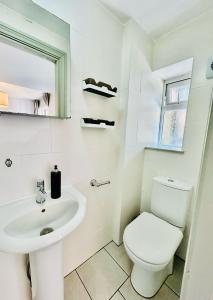 a white bathroom with a toilet and a sink at Heart of Dalston East London in London