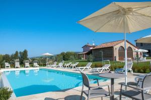 uma piscina com cadeiras, uma mesa e um guarda-sol em AGRITURISMO La COLLINA del SOLE em Coltavolino