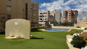 a backyard with a pool and grass and buildings at Increíble casa frente a la playa de Muchavista Alicante By ElConserje in El Campello