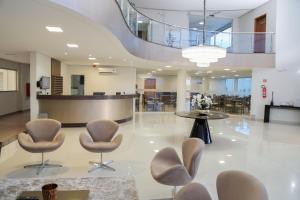 a lobby with chairs and a table in a building at Rota Hoteis Itumbiara in Itumbiara