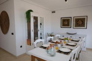 a white dining room with a table with food on it at Increíble casa frente a la playa de Muchavista Alicante By ElConserje in El Campello