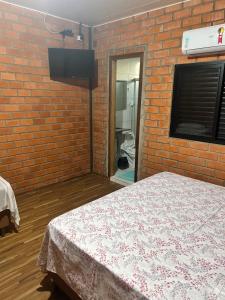 una stanza con un letto e un muro di mattoni di Hotel Raffa a Bandeirantes
