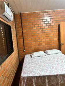 una camera da letto con un letto e una parete in mattoni di Hotel Raffa a Bandeirantes