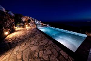 a swimming pool at night with the ocean in the background at Castria studios in Kionia