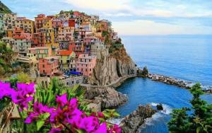 un gruppo di case colorate su una scogliera vicino all'oceano di Lovely House with private pool 3X2 with jacuzzi and breakfast with garden and BBQ next seaside and train station a Sarzana
