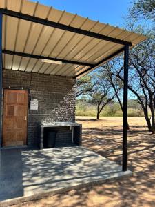 a wooden pergola on a brick building with a door at Northern Rock Campsites in Otjiwarongo