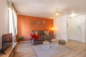 a living room with a couch and a tv at Le Corallo - T2 cosy et moderne en hyper-centre in Bergerac +7 photos