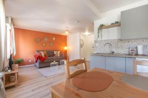 a kitchen and living room with a couch and a table at Le Corallo - T2 cosy et moderne en hyper-centre in Bergerac
