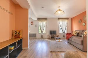 a living room with a couch and a tv at Le Corallo - T2 cosy et moderne en hyper-centre in Bergerac
