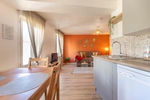 a kitchen and living room with an orange wall at Le Corallo - T2 cosy et moderne en hyper-centre in Bergerac