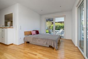 a white bedroom with a bed and a balcony at Seeliebe und Gartenglück in Bodman-Ludwigshafen