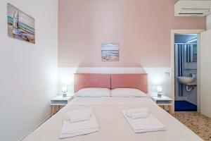 a bedroom with a large bed with two white towels at HOTIDAY Ortigia Opera in Syracuse