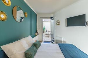 1 dormitorio con cama, espejo y TV en Le Néo - Studio chic avec sa cour privative et fibre, en Bergerac