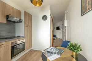 una pequeña cocina con una mesa y un reloj en la pared en Le Néo - Studio chic avec sa cour privative et fibre, en Bergerac