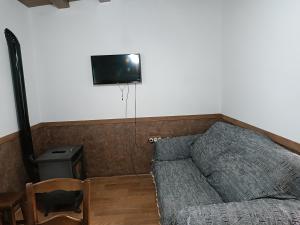 Una sala de estar con un sofá y un televisor en la pared. en Casa Rural El Albergue, en Beires