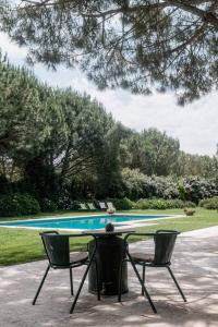 un tavolo da ping pong e due sedie davanti a una piscina di Lugar das Sesmarias a Pinhal Novo
