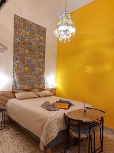 a bedroom with a bed with a table and a yellow wall at Suite La TERRAZZA ILLUMINATA in Trapani