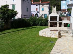 a backyard with a stone fireplace in the grass at Holiday Home Casa Matilde in Koromačno +8 photos