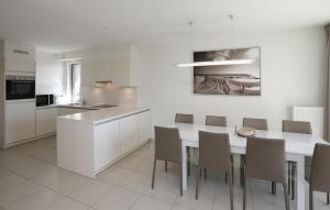 Una cocina blanca con una mesa de comedor y sillas. en Residentie Crystal Ref 84, en Ostende
