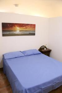 a bedroom with a blue bed with a painting on the wall at Corte Micetti 2- Centro storico in Gallipoli