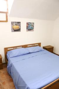 a bedroom with a blue bed with pictures on the wall at Corte Micetti 1- Centro storico in Gallipoli