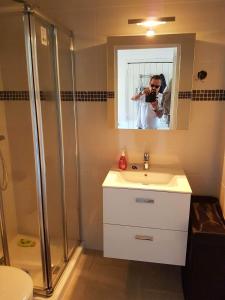 un homme prenant une photo d'une salle de bains avec lavabo et douche dans l'établissement Studio Corse avec acces direct à la plage La Liscia, à Calcatoggio