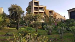 un bâtiment avec un jardin en face dans l'établissement Studio Corse avec acces direct à la plage La Liscia, à Calcatoggio
