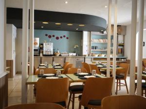a restaurant with tables and chairs and a kitchen at Hôtel de Lyon in Valence