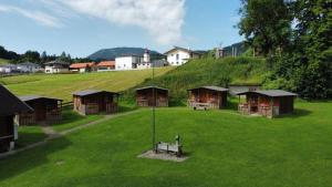 un gruppo di capanne su un campo verde con una collina di Zelt oder Camper Stellplatz am Campingplatz Raddörfl a Teufenbach