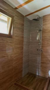 a bathroom with a shower with wooden walls and a window at Log Cabin Plavšić - Vikendica Plavšić in Šipovo +17 photos