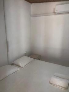 a small white room with a bed and two towels at Barreira Beachfront Room 5 in Kalamata