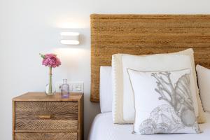 Una cama con un jarrón de flores en una mesita de noche en Todimer astrid lux, en Motril