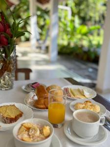 a table with plates of food and a glass of orange juice at Pousada Recanto Itaguá in Ubatuba