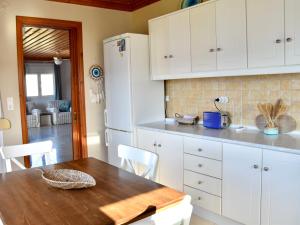 a kitchen with a wooden table and white cabinets at Deep Blue Apartments in Karpathos +6 photos