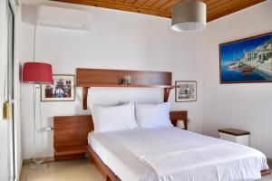 a bedroom with a white bed with a red lamp at Deep Blue Apartments in Karpathos