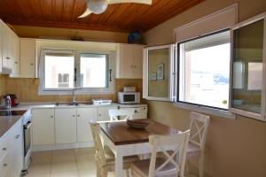 a kitchen with a wooden table and chairs and windows at Deep Blue Apartments in Karpathos