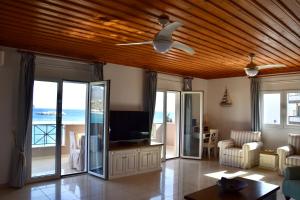 a living room with a ceiling fan and a television at Deep Blue Apartments in Karpathos