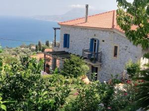 a house with blue windows and the ocean in the background at Stone house 1883 Kymi with pool in Enoría