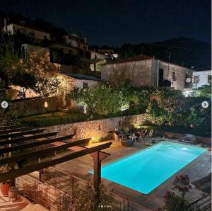 a swimming pool in a yard at night at Stone house 1883 Kymi with pool in Enoría