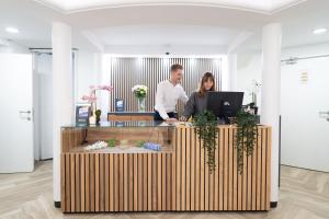a man and woman standing at a desk with a computer at Hotel Le Grand Colombier in Brussels