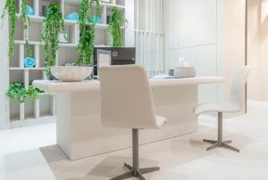 a white reception desk with two chairs and plants at Hotel Verde Mar & SPA in Ribeira Grande